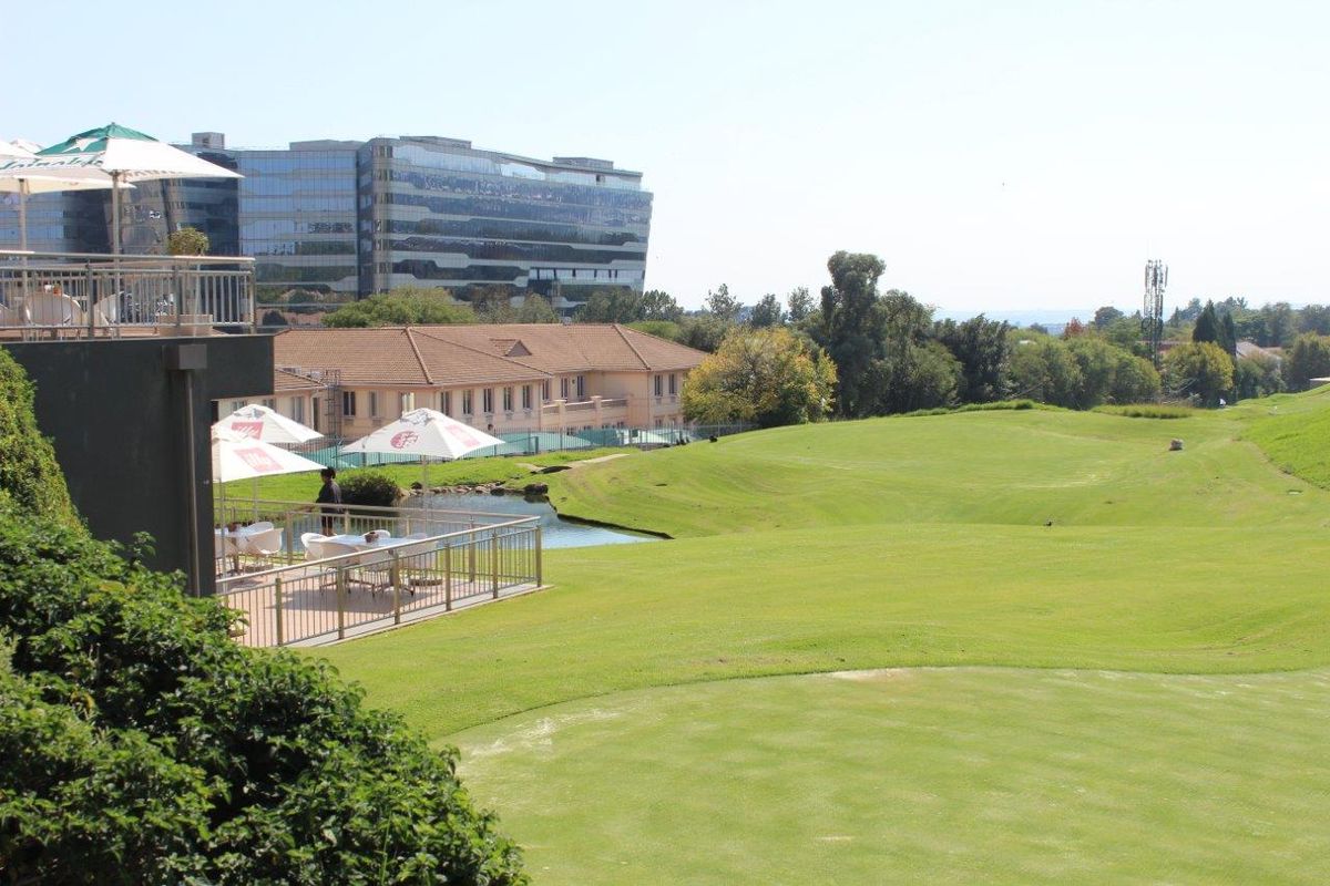 Elevated view overlooking a manicured golf course, water feature, and surrounding office park infrastructure.