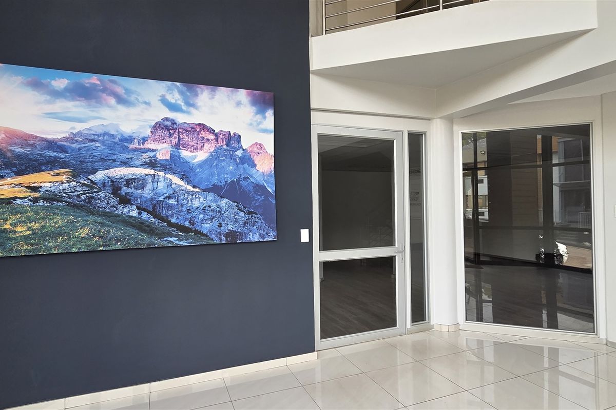 Modern office building entrance lobby featuring tiled flooring, glass doors, and a directory board for ground and first-floor tenants.