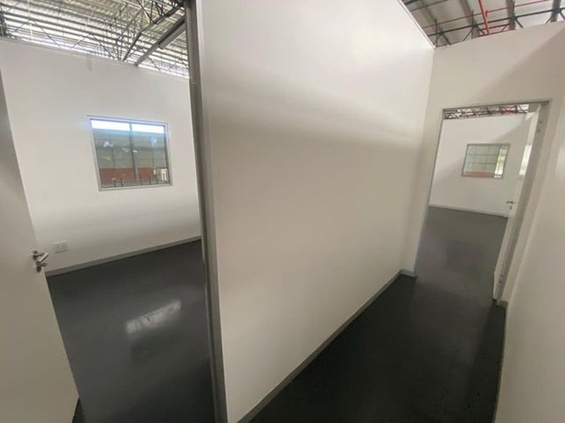 A clean, modern office space within an industrial unit, featuring partition walls, epoxy flooring, and an exposed ceiling structure.