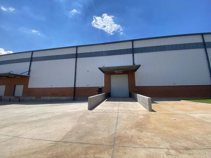 Industrial warehouse exterior featuring a concrete loading dock, roller shutter door, and durable metal and brick facade construction.