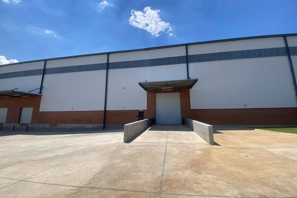 Industrial warehouse exterior featuring a concrete loading dock, roller shutter door, and durable metal and brick facade construction.