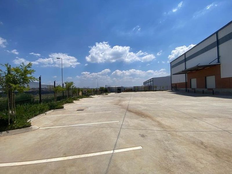 Spacious industrial concrete yard and parking area featuring secure perimeter fencing and direct access to warehouse loading bays.