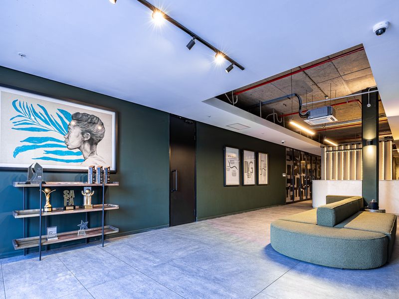 Modern industrial-style office entrance featuring exposed concrete ceilings, track lighting, tiled floors, and a sleek reception area.