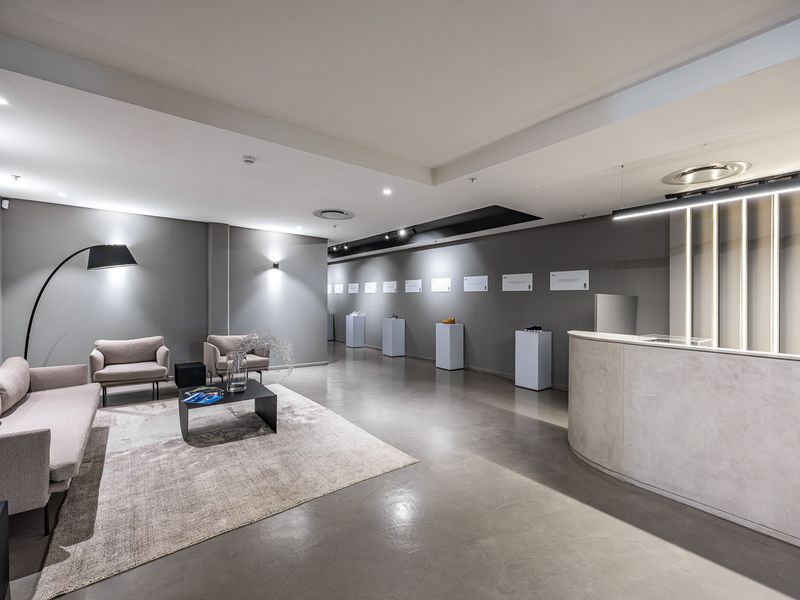 Modern industrial-style reception area featuring a curved concrete desk, polished concrete floors, and professional recessed lighting throughout the space.