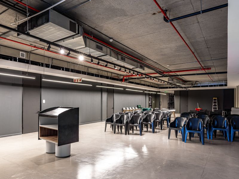 A modern industrial-style open plan space featuring exposed concrete ceilings, visible HVAC ducting, fire sprinkler systems, and polished concrete floors.