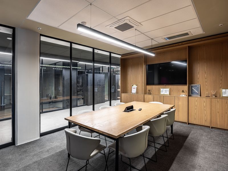 Modern professional boardroom featuring high-quality timber cabinetry, glass partitioning, integrated climate control, and sleek linear lighting for a polished corporate environment.