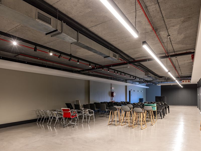 Spacious open-plan industrial area featuring polished concrete floors, exposed ceiling infrastructure, and modern linear lighting, suitable for versatile commercial or office use.