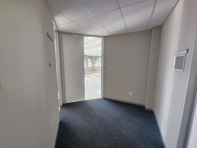 A clean, empty office space featuring neutral walls, carpeted flooring, and a suspended ceiling, providing a versatile environment for professional use.