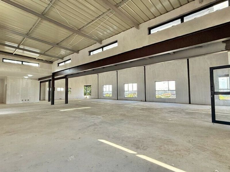 Spacious open-plan office area featuring exposed steel structural beams, high-level clerestory windows, and unfinished concrete flooring, offering a blank canvas for custom fit-out.