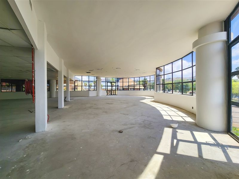 Spacious open-plan office area featuring extensive floor-to-ceiling windows, structural columns, and an unfinished concrete floor, offering a blank canvas for custom fit-out.