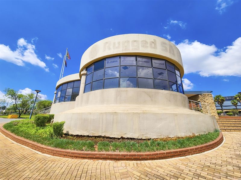 Exterior view of a modern office building featuring a distinctive curved concrete facade, large glass windows, and a paved entrance area.