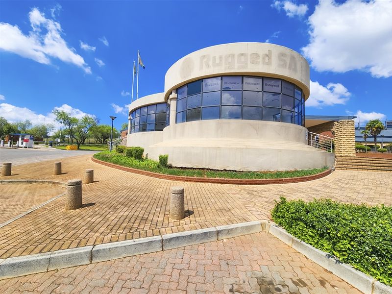 Front exterior view of a modern office building featuring a distinctive curved glass facade and paved entrance area.