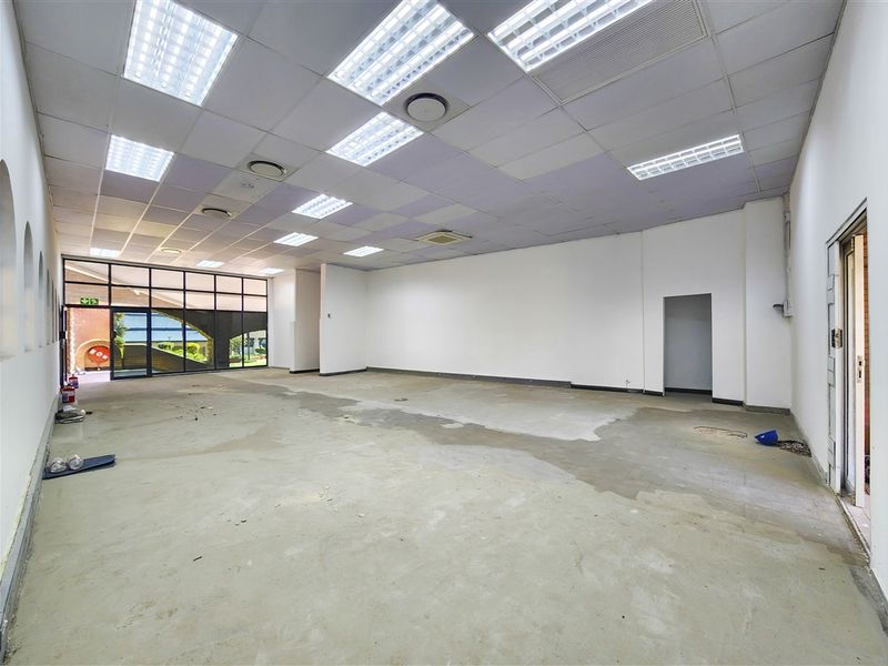 A spacious, vacant office unit featuring a suspended ceiling with recessed lighting, large glass windows, and unfinished concrete flooring, ready for custom fit-out.