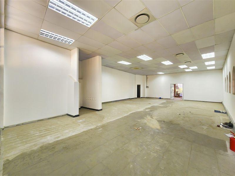 A spacious, vacant office area featuring a suspended ceiling with recessed lighting and unfinished concrete flooring, ready for custom fit-out.