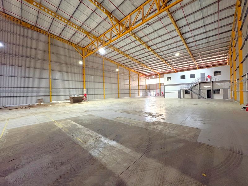 Spacious industrial warehouse featuring a high-clearance steel portal frame, concrete flooring, and an integrated mezzanine level with staircase access.