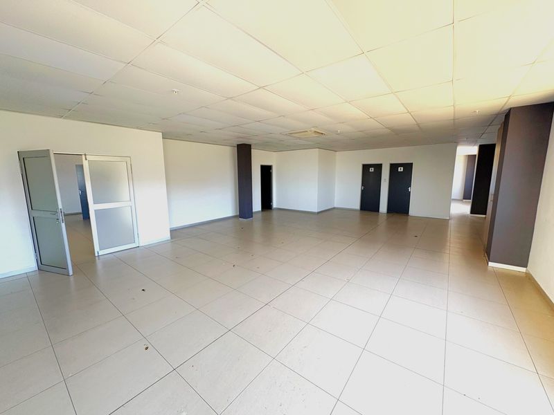 Spacious open-plan industrial office area featuring tiled flooring, a suspended ceiling, and multiple internal access points.