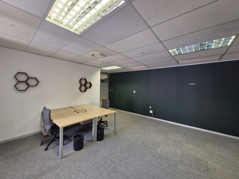 A professional office space featuring a suspended ceiling with recessed lighting, carpeted flooring, and a dark accent wall.