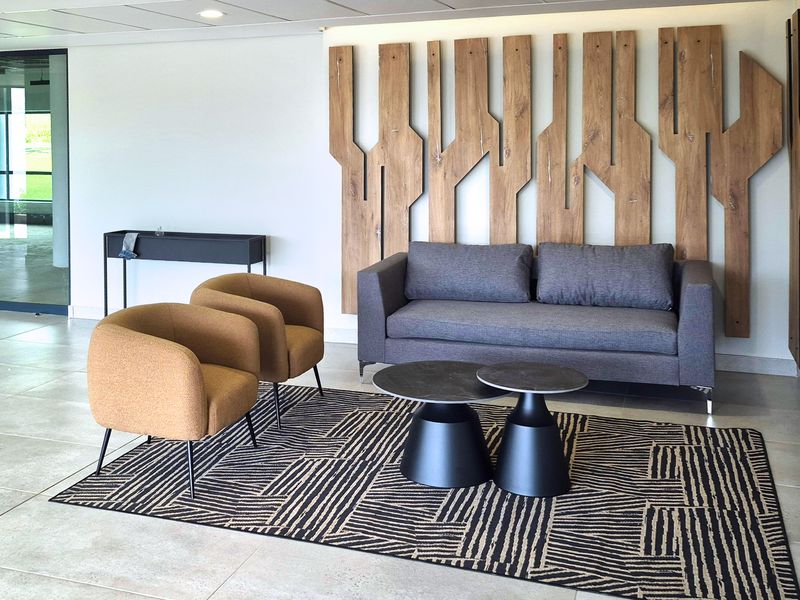 A modern industrial-style reception or lounge area featuring tiled flooring, recessed ceiling lights, and a prominent decorative timber wall feature.