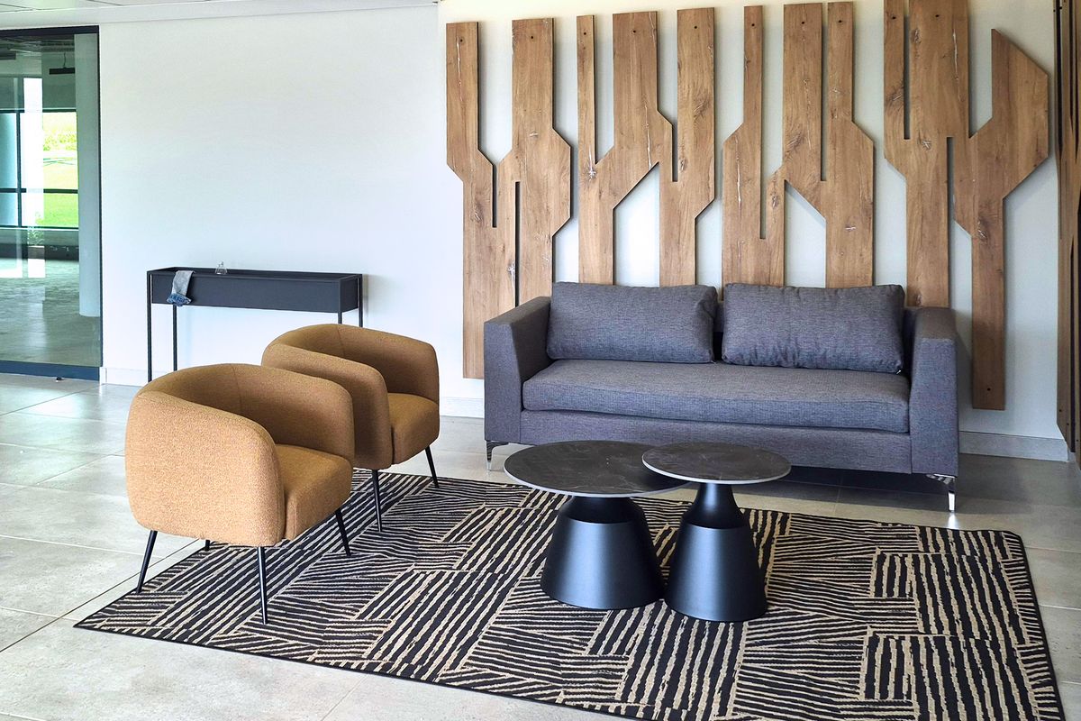A modern industrial-style reception or lounge area featuring tiled flooring, recessed ceiling lights, and a prominent decorative timber wall feature.