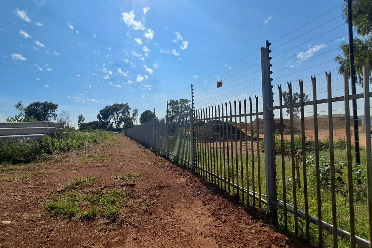 A view of the vacant commercial land featuring perimeter steel palisade fencing topped with an electric fence system.