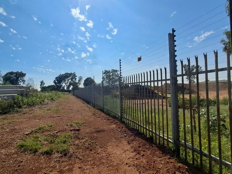 A view of the vacant commercial land featuring perimeter steel palisade fencing topped with an electric fence system.