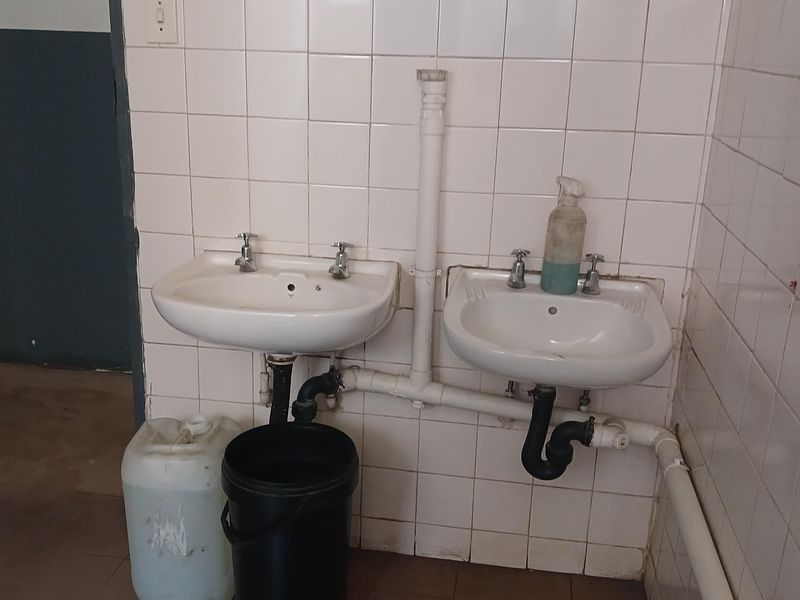 Industrial wash area featuring dual wall-mounted ceramic basins with exposed plumbing and tiled splashbacks.