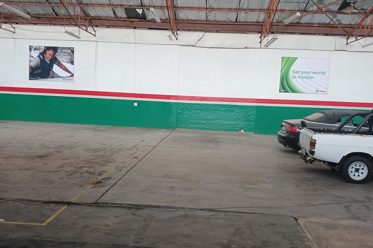 Spacious industrial warehouse interior featuring high exposed steel truss ceilings, concrete flooring, and painted wall finishes suitable for workshop or storage use.