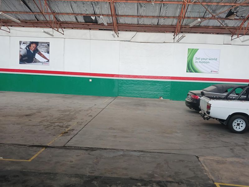 Spacious industrial warehouse interior featuring high exposed steel truss ceilings, concrete flooring, and painted wall finishes suitable for workshop or storage use.