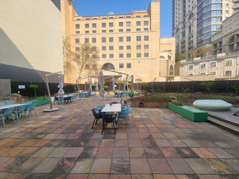 Spacious outdoor patio area featuring paved flooring, raised garden beds, and perimeter fencing, suitable for office break-out space or outdoor meetings.