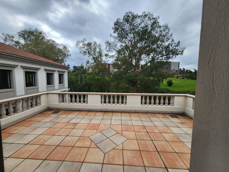 Spacious outdoor balcony featuring tiled flooring and a classic balustrade, offering pleasant views of the surrounding greenery and neighborhood.