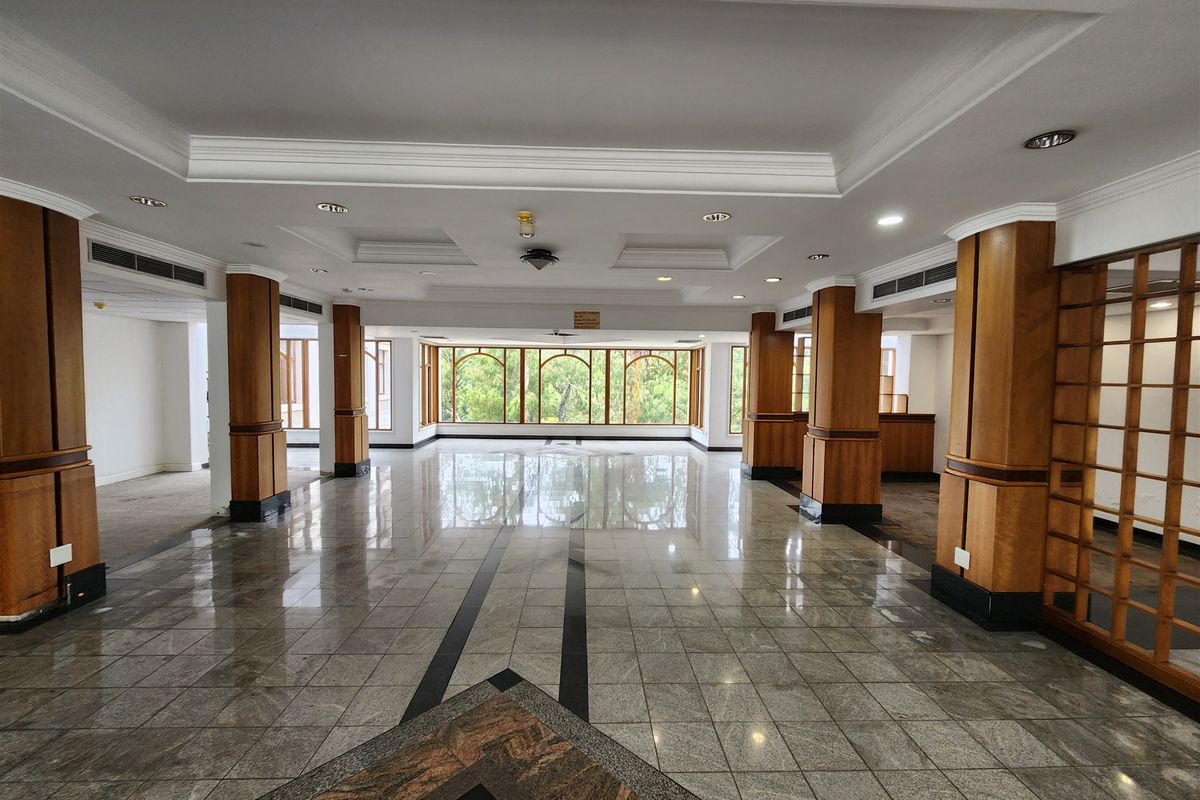 Spacious, open-plan office area featuring polished granite flooring, decorative wooden columns, and large windows providing ample natural light.