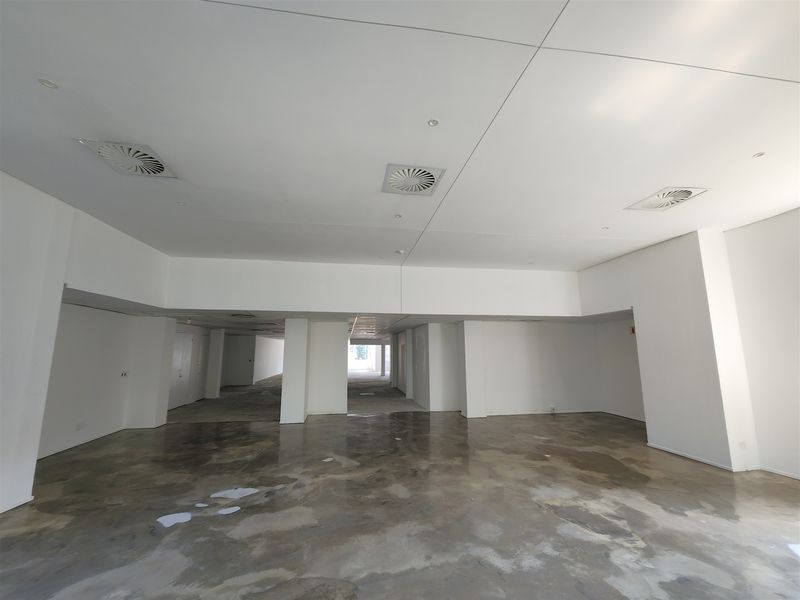 A spacious, open-plan office area featuring polished concrete floors, recessed ceiling air conditioning vents, and clean white walls, ready for custom fit-out.