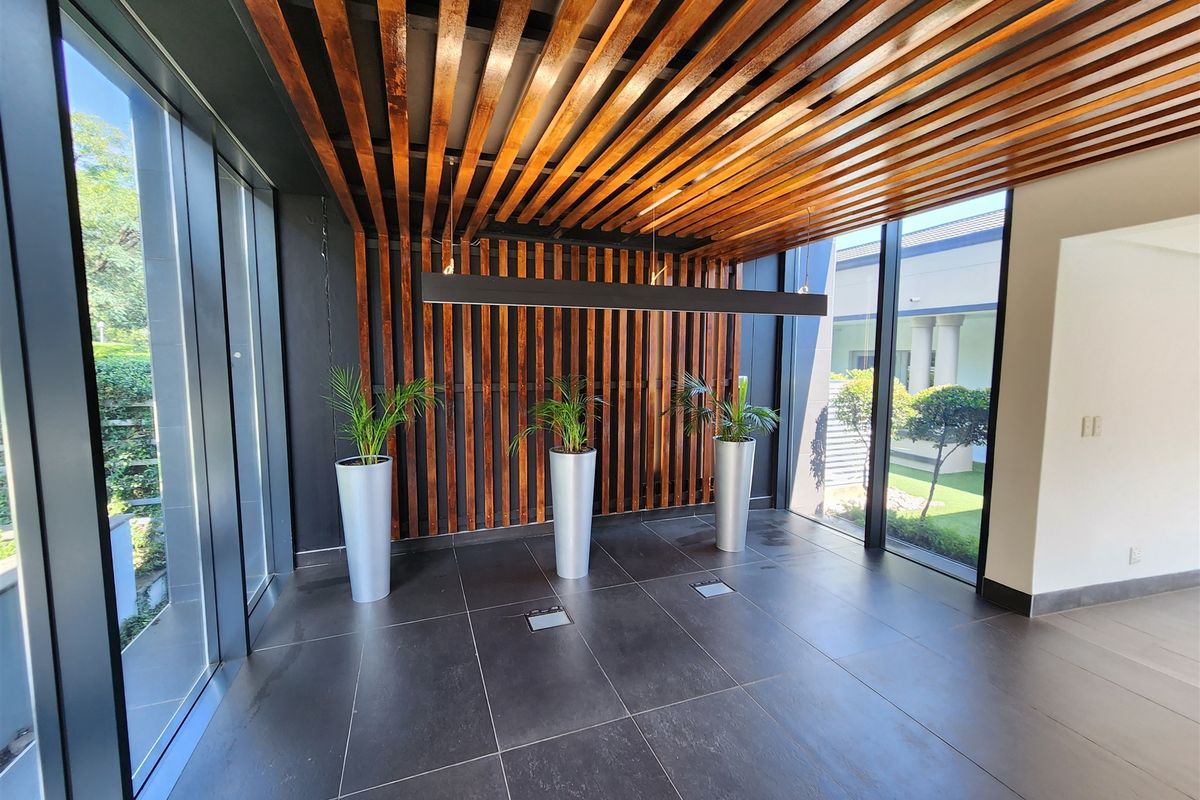 Modern office entrance featuring a striking timber slat ceiling and wall design, large format floor tiles, and expansive floor-to-ceiling glass windows.