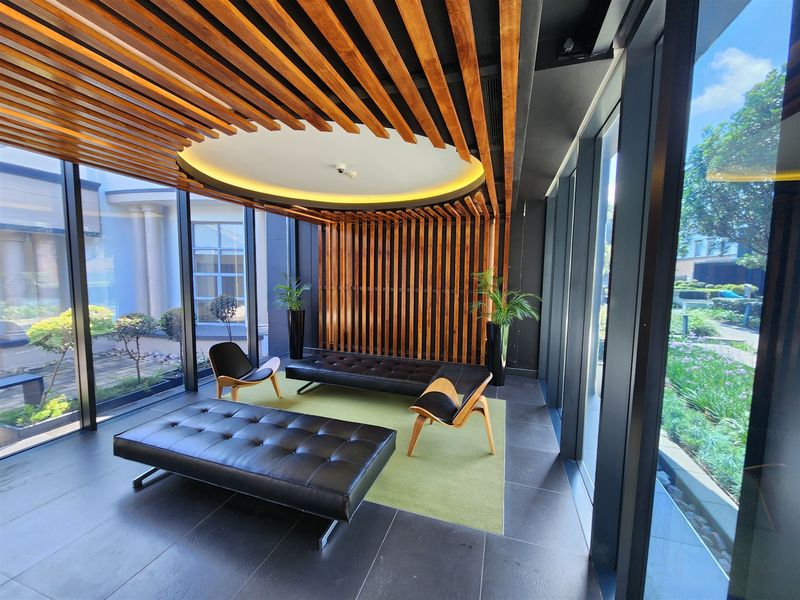 Modern office reception or lounge area featuring a striking timber slat ceiling and wall design, floor-to-ceiling windows, and high-quality tiled flooring.