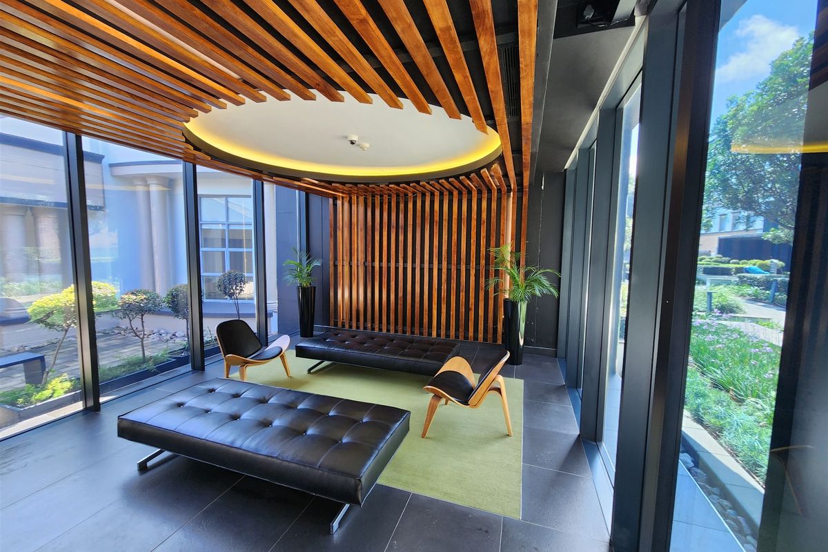 Modern office reception or lounge area featuring a striking timber slat ceiling and wall design, floor-to-ceiling windows, and high-quality tiled flooring.
