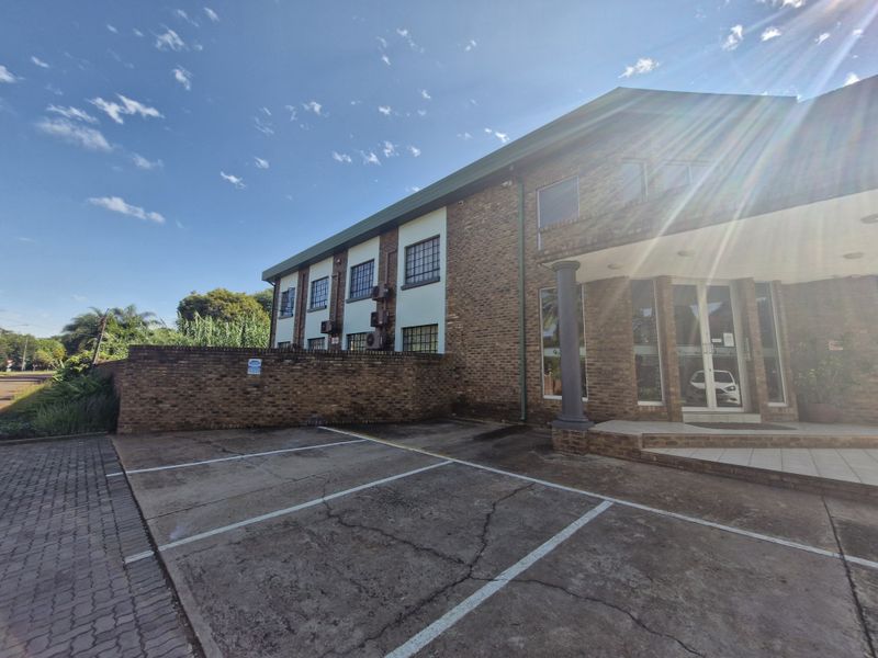 Front exterior view of a commercial building featuring a brick facade, glass entrance, and dedicated paved parking bays.