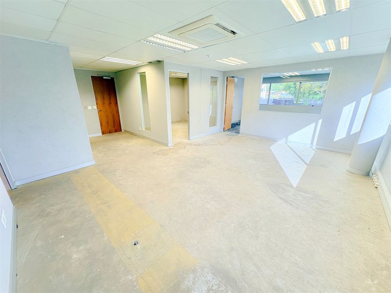 An open-plan office space featuring a suspended ceiling, recessed lighting, integrated air conditioning, and internal glass partitions, ready for custom fit-out.