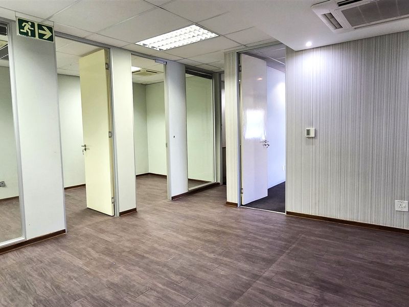 A vacant office suite featuring glass partitions, laminate flooring, recessed ceiling lighting, and integrated air conditioning, providing a clean and professional workspace environment.