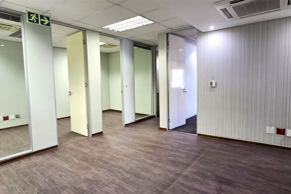A vacant office suite featuring glass partitions, laminate flooring, recessed ceiling lighting, and integrated air conditioning, providing a clean and professional workspace environment.