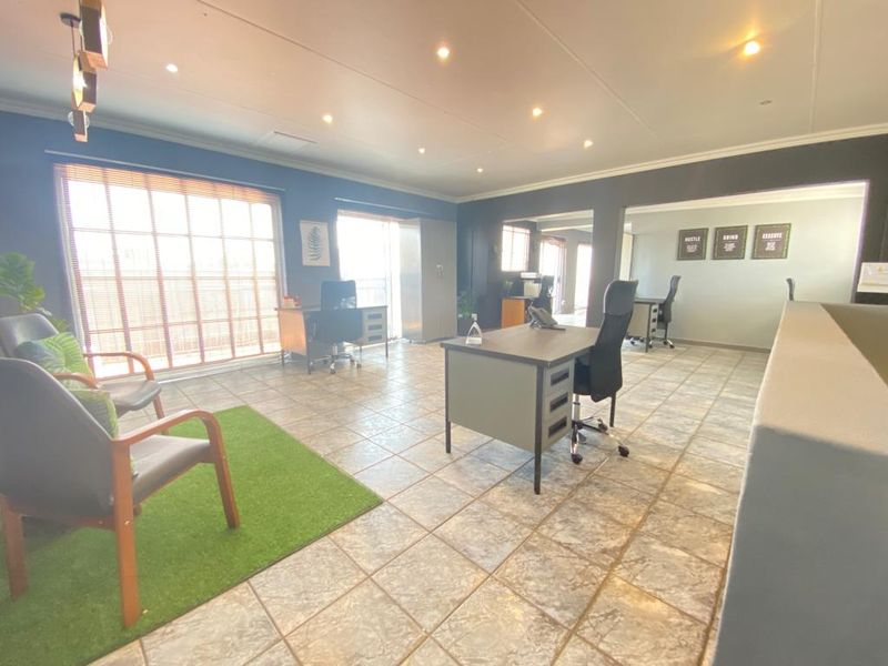 Spacious commercial office area featuring tiled flooring, recessed downlighting, and large windows with venetian blinds, providing a bright and professional workspace.