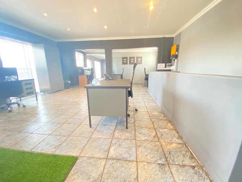 A spacious commercial office area featuring tiled flooring, recessed downlighting, and a functional partition wall layout suitable for a professional workspace.