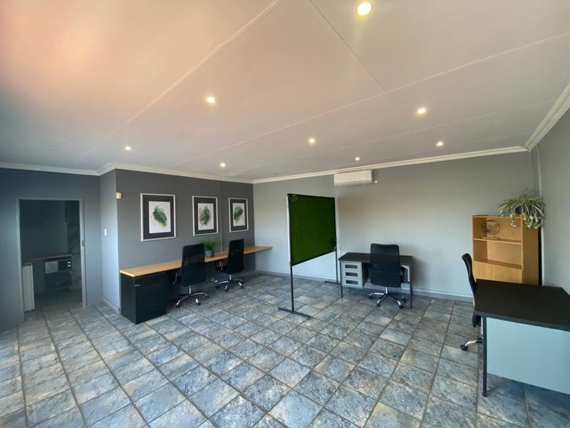 A functional commercial office space featuring tiled flooring, recessed downlighting, and a split-system air conditioning unit.
