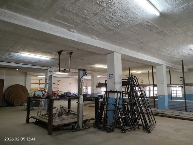 Spacious industrial utility area featuring concrete flooring, exposed structural columns, and overhead fluorescent lighting, suitable for manufacturing or storage operations.