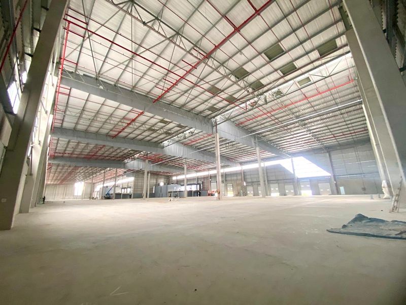 Expansive industrial warehouse space featuring high-bay ceilings, exposed steel structural framing, integrated fire sprinkler systems, and polished concrete flooring.