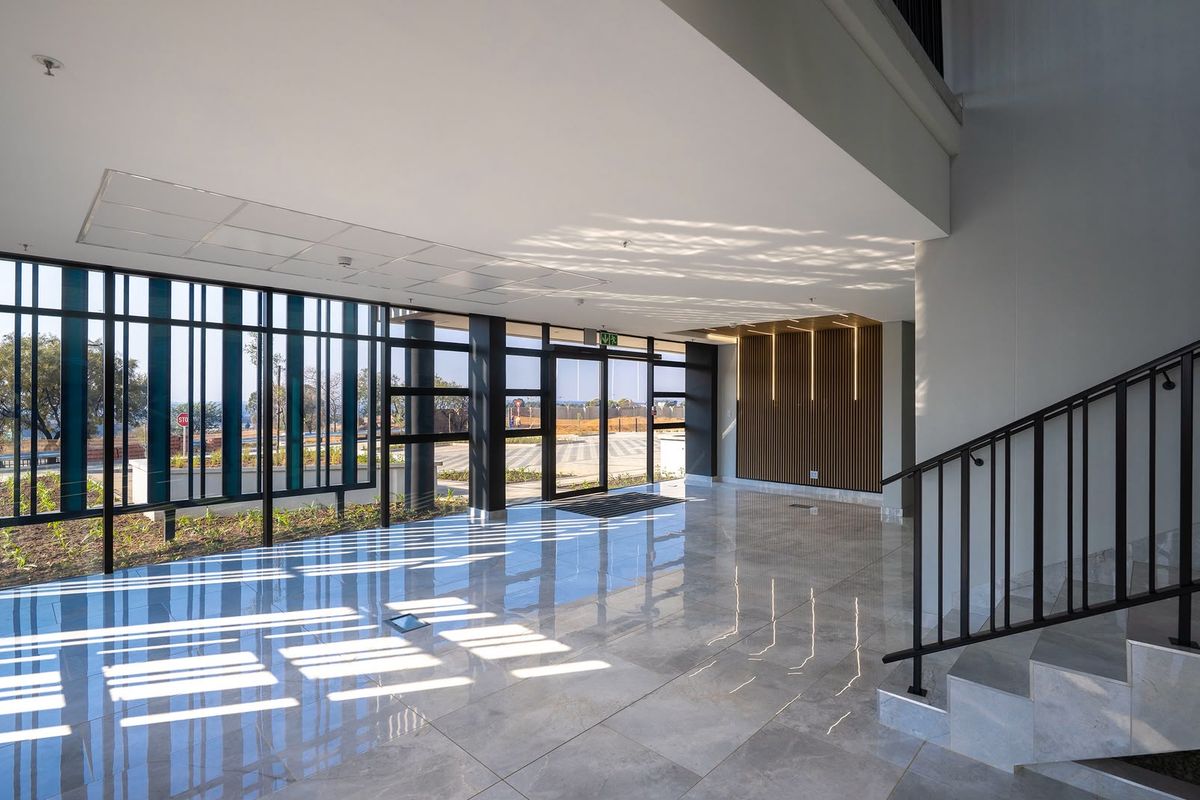 Modern industrial entrance lobby featuring high-gloss tiled flooring, floor-to-ceiling glass windows, and a contemporary slatted timber feature wall.