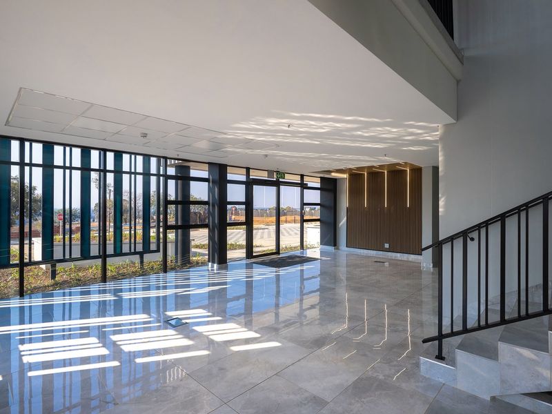 Modern industrial entrance lobby featuring high-gloss tiled flooring, floor-to-ceiling glass windows, and a contemporary slatted timber feature wall.