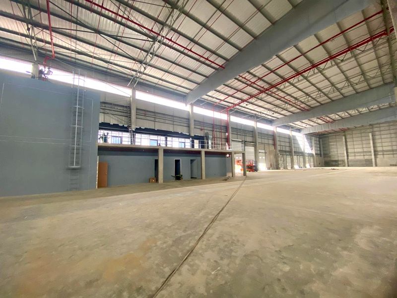 Spacious industrial warehouse featuring high ceilings, exposed steel roof structure, fire sprinkler system, concrete flooring, and an integrated mezzanine level.