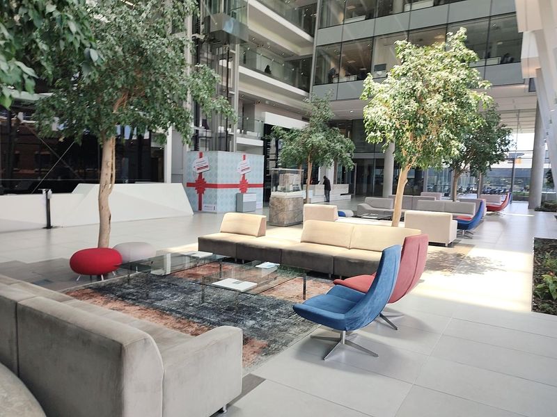Spacious modern office building atrium featuring high ceilings, glass curtain walls, and a bright, open-plan reception or lounge area.
