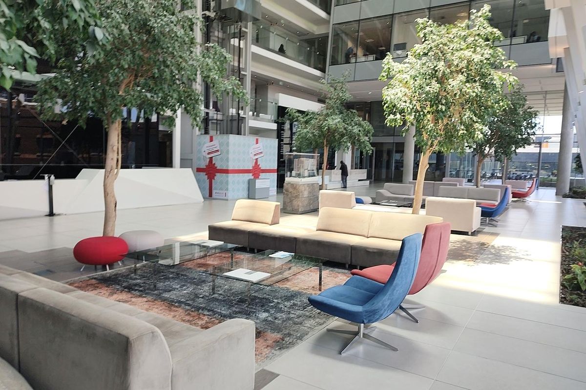 Spacious modern office building atrium featuring high ceilings, glass curtain walls, and a bright, open-plan reception or lounge area.