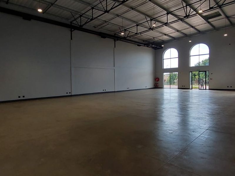 Spacious open-plan retail or commercial unit featuring high exposed ceilings, polished concrete flooring, and large arched windows providing ample natural light.